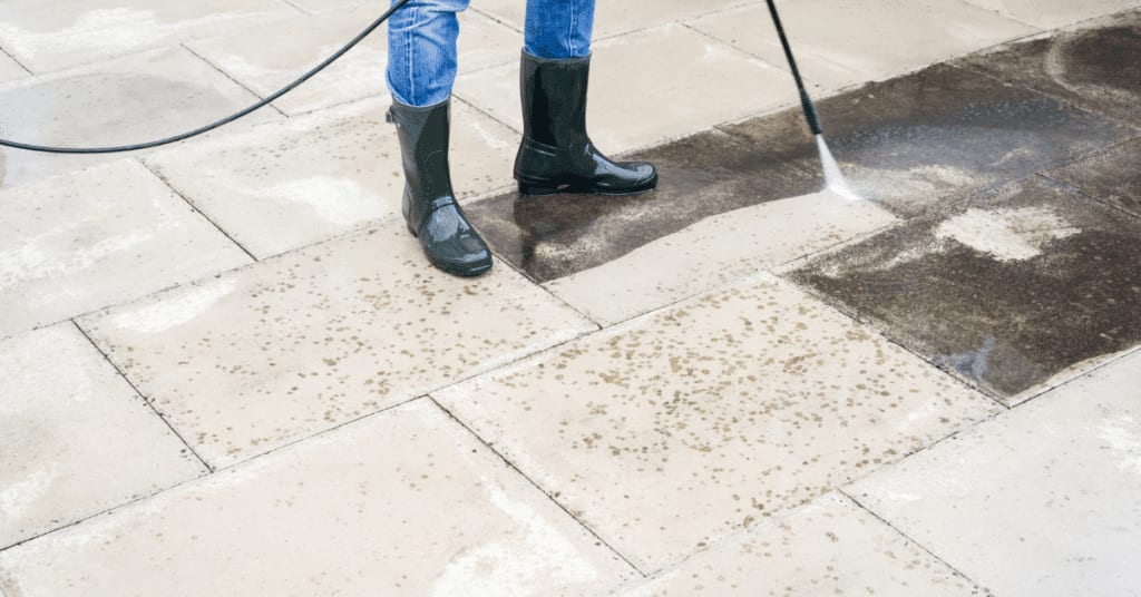 a man showing only his two feet, wearing boots, working on a commercial power washing job