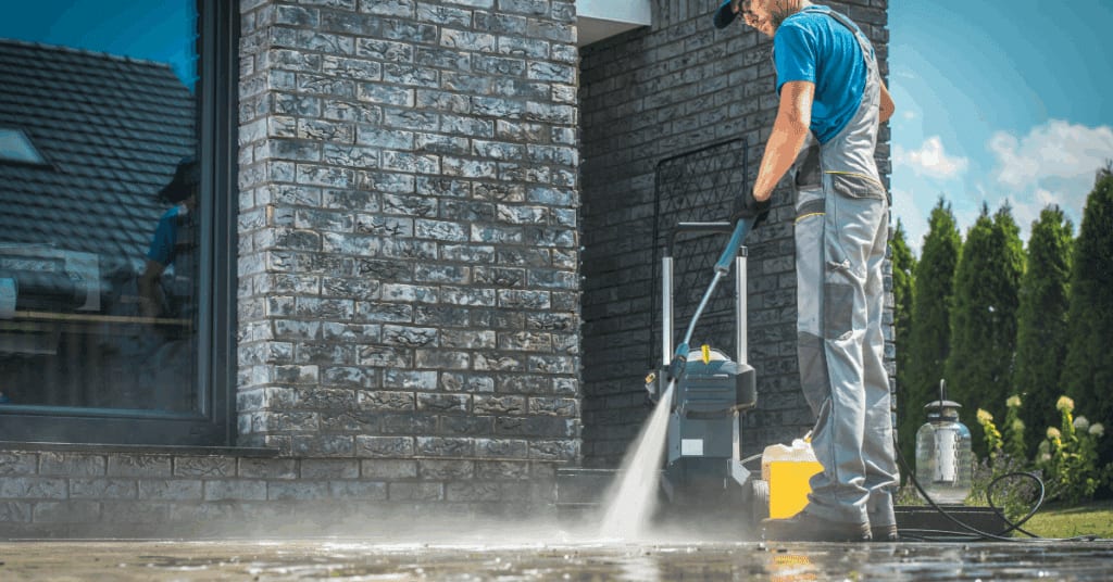 a man holding a hose doing power washing outside the building
