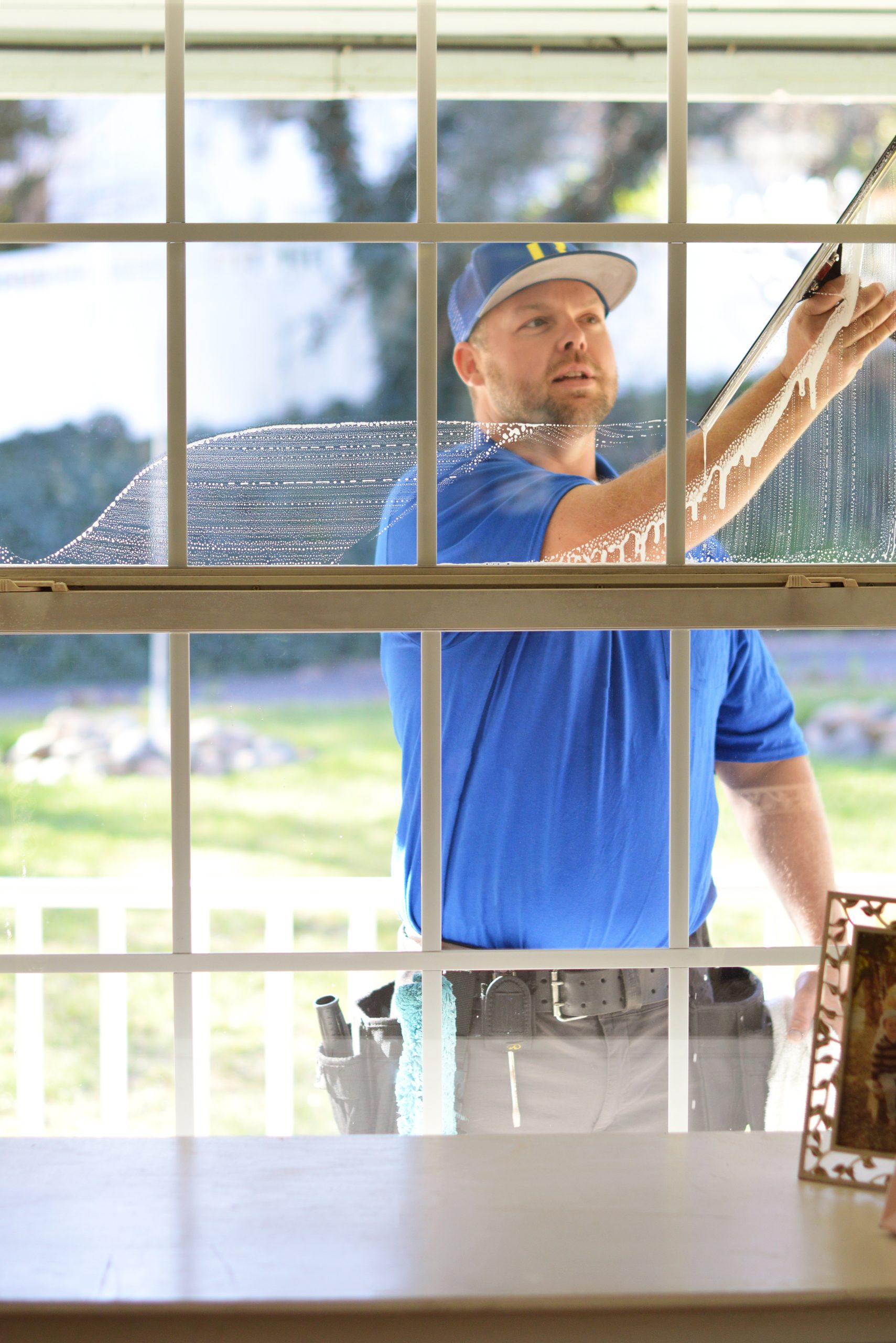 A Bailey Boys technician squeegeeing a home's window to a streak-free finish in the Sacramento area