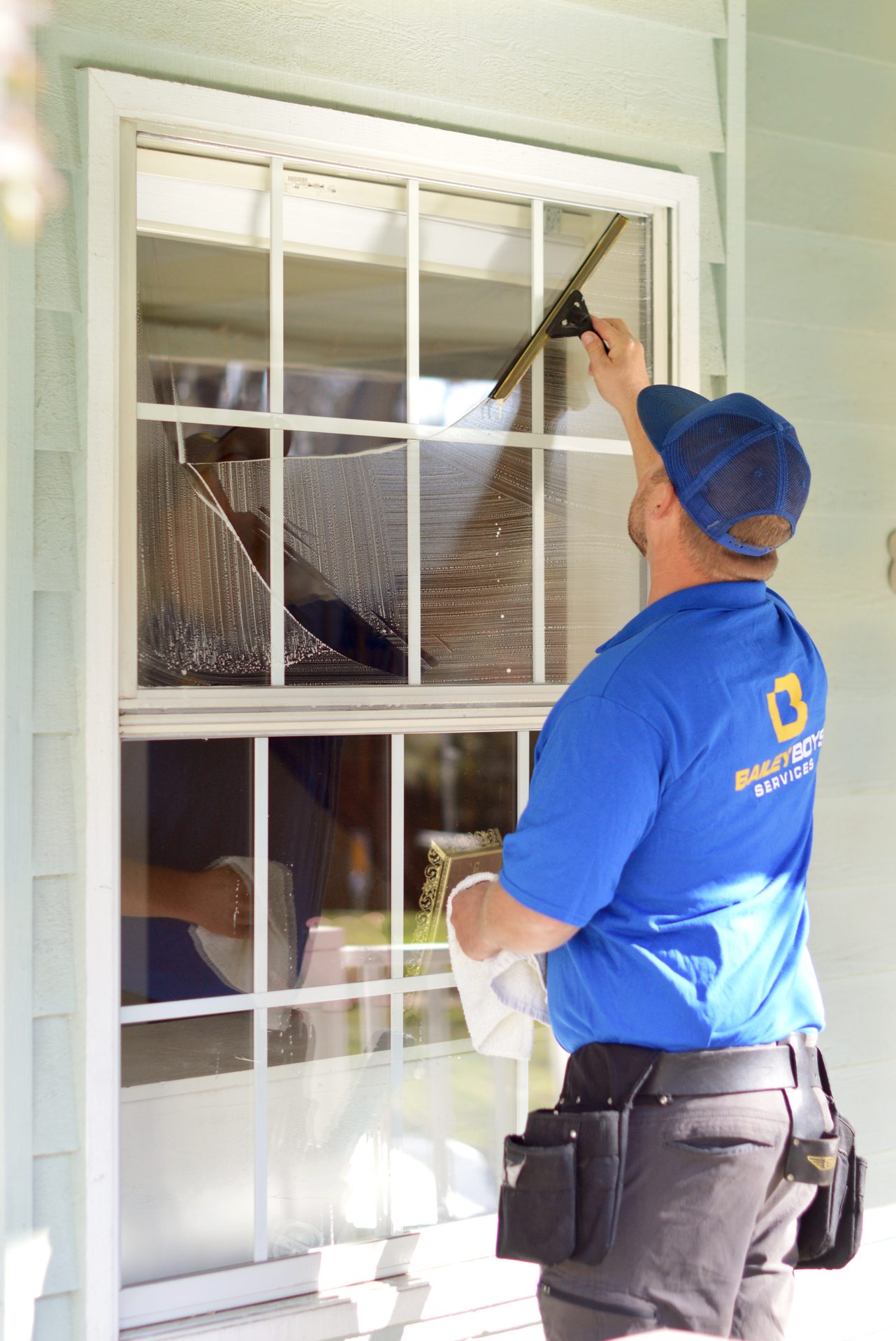 A technician cleaning a large residential window in the Sacramento area